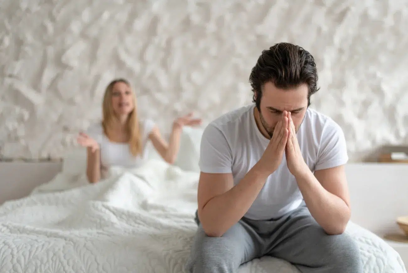 man upset over libido problems with wife sitting on edge of bed