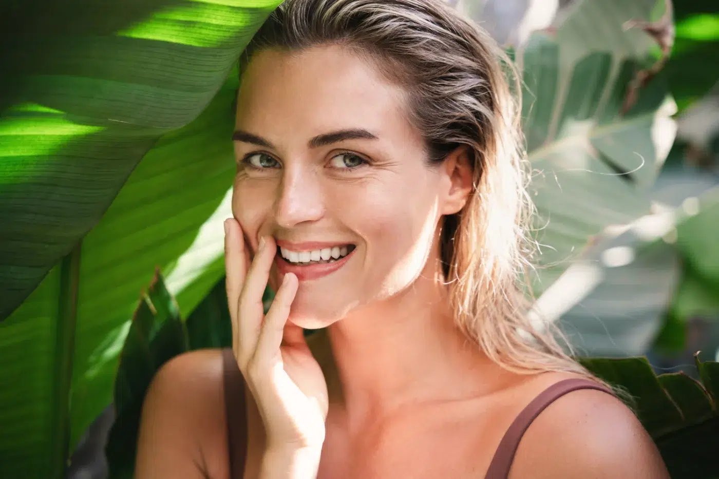 smiling woman in front of leaves