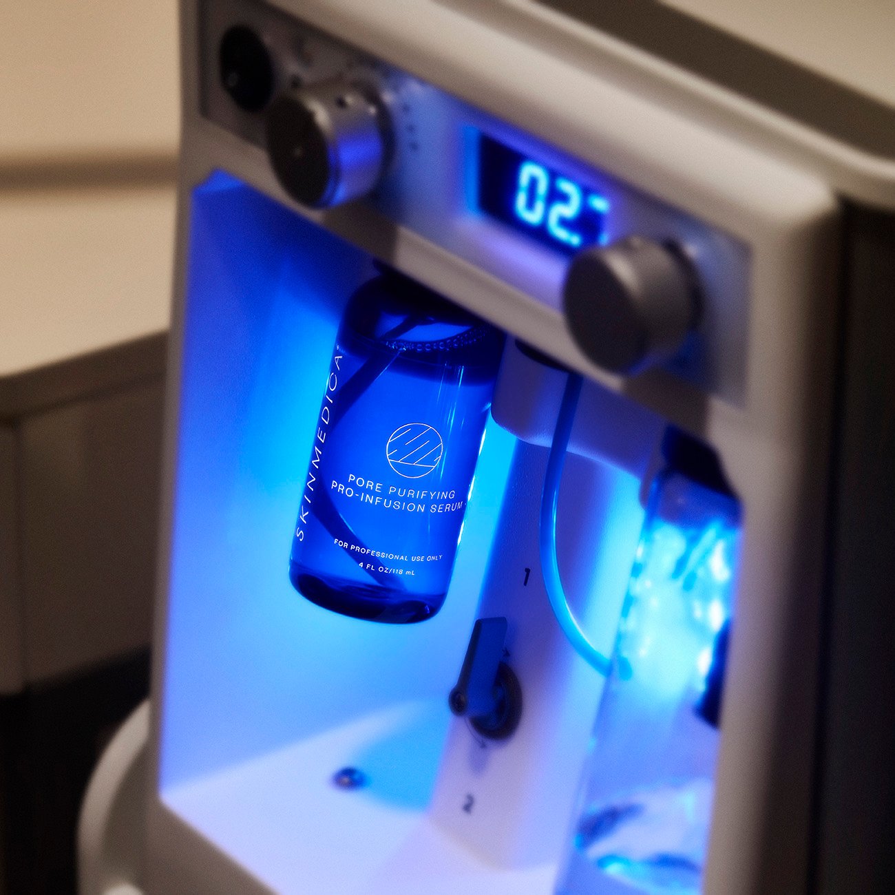 SkinMedica Pore Purifying Pro-Infusion Serum bottle in a blue-lit spa device.