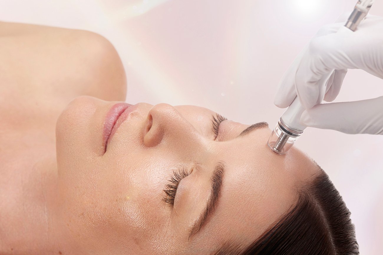 Woman receiving a professional facial treatment with a skincare device.